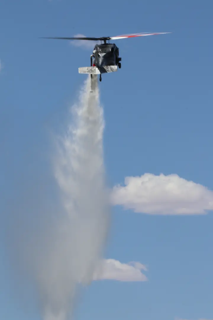 Black Hawk releasing a water drop against a blue sky