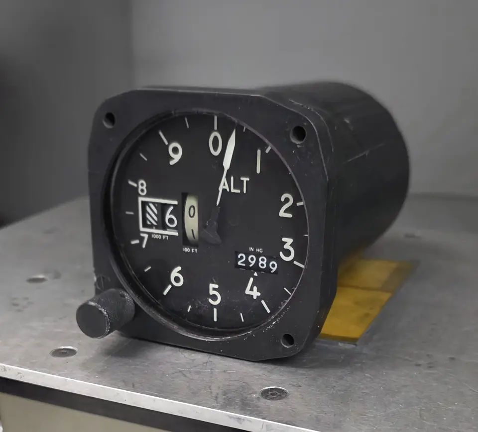 Aircraft altimeter with a barometric setting window on a metal workbench