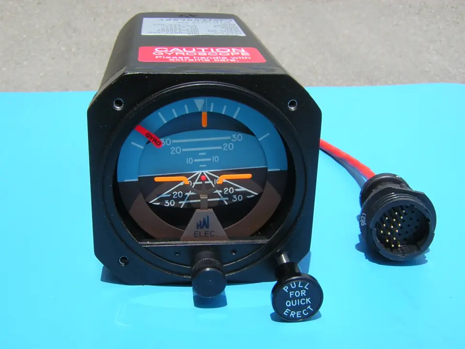 Electric attitude indicator with its round wiring connector, on a blue workbench mat