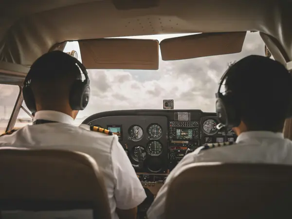 Instructor and student pilot side by side in a training airplane, seen from the back seat