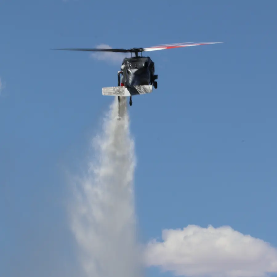 Black Hawk releasing a water drop against a blue sky