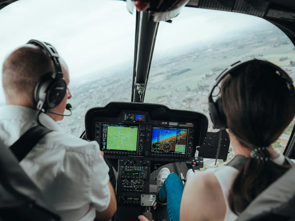 Garmin glass-cockpit displays in a helicopter panel, with the pilot and a passenger in flight